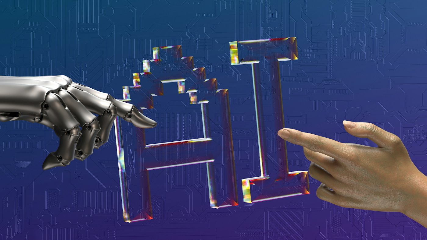 Una mano robotica e una mano umana si avvicinano alla scritta AI